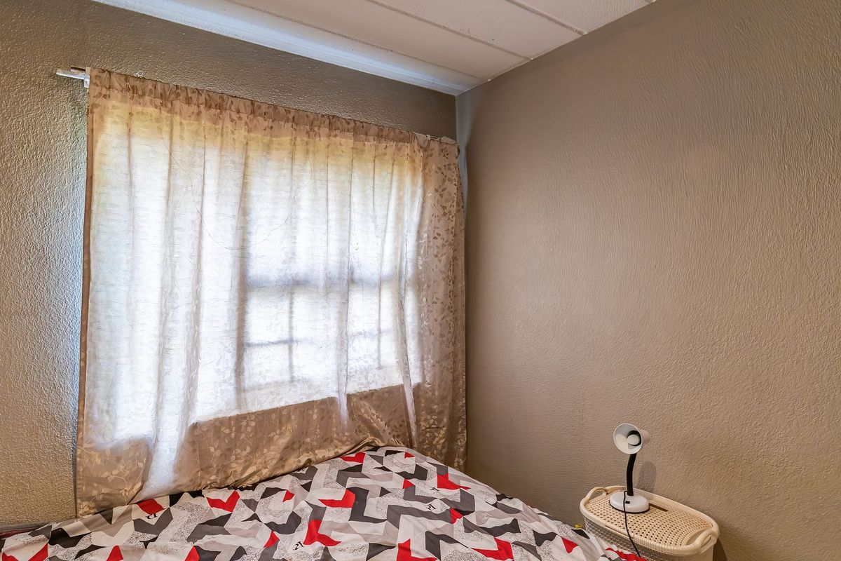 A bedroom featuring a window with a curtain rod and neutral wall finishes.