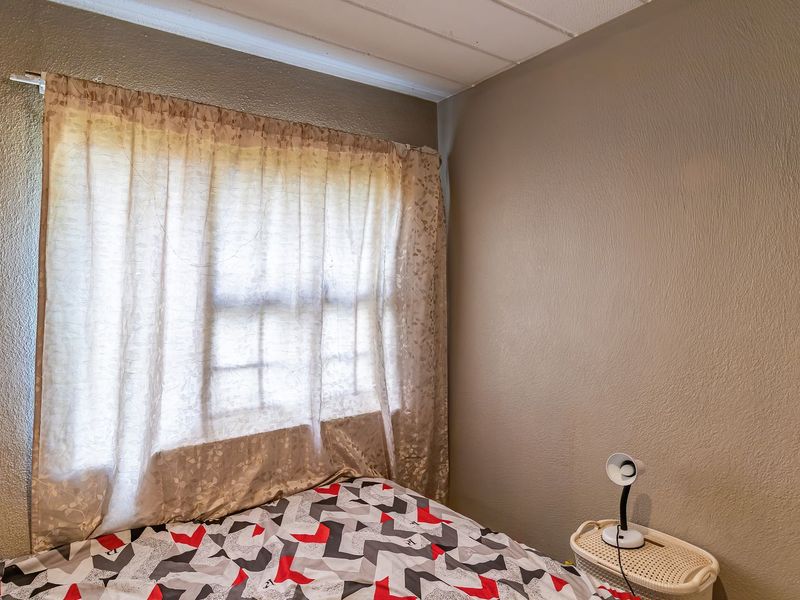 A bedroom featuring a window with a curtain rod and neutral wall finishes.