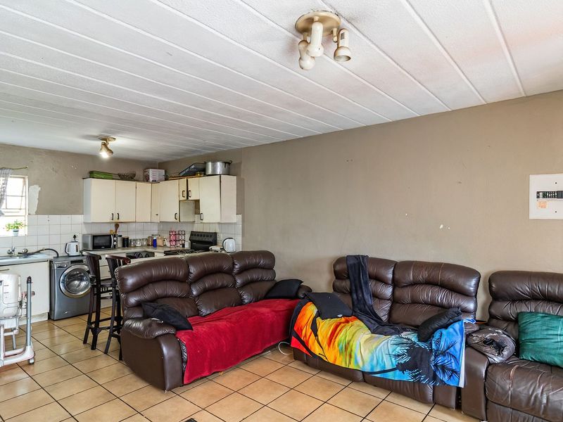 Open-plan living area featuring tiled flooring, a compact kitchen with built-in cabinetry, and a functional layout suitable for modern updates.