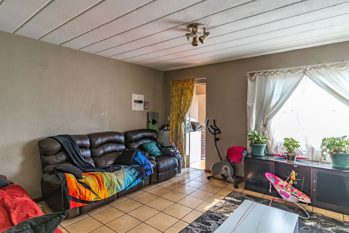 A living room featuring tiled flooring and a ceiling light fixture, with potential for cosmetic updates to the walls and ceiling.
