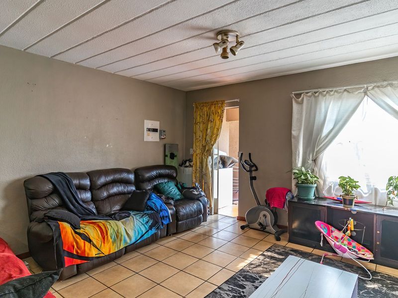 A living room featuring tiled flooring and a ceiling light fixture, with potential for cosmetic updates to the walls and ceiling.