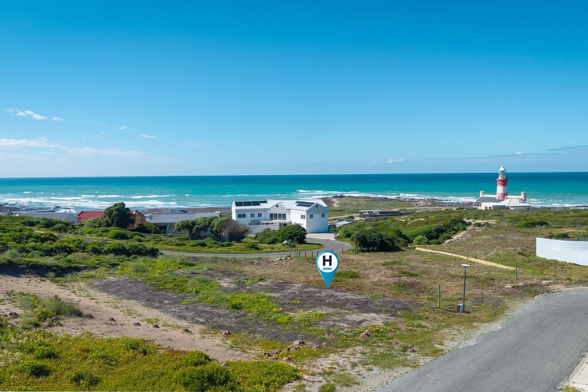 An aerial view of a vacant residential plot situated in a coastal area, featuring proximity to the ocean and a local lighthouse.