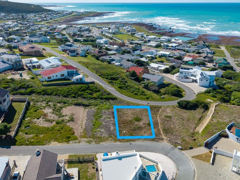 An aerial view of a vacant residential plot situated in a coastal neighborhood, highlighting its location and proximity to the ocean.