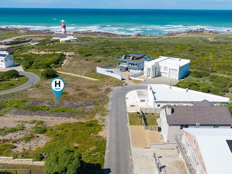 Aerial view of a vacant residential plot situated in a coastal neighborhood, featuring proximity to the local lighthouse and ocean views.
