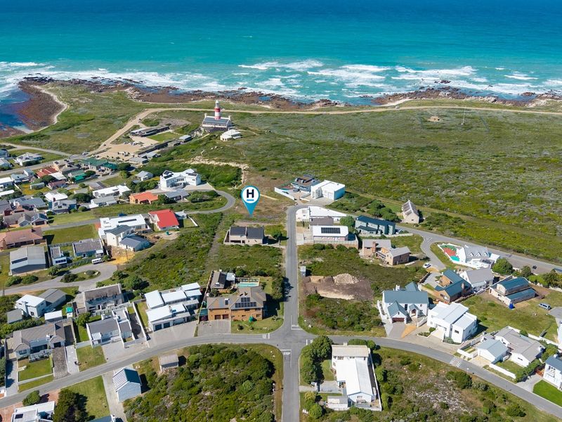 Aerial view of a vacant residential plot situated in a coastal neighborhood, offering proximity to the ocean and local lighthouse.