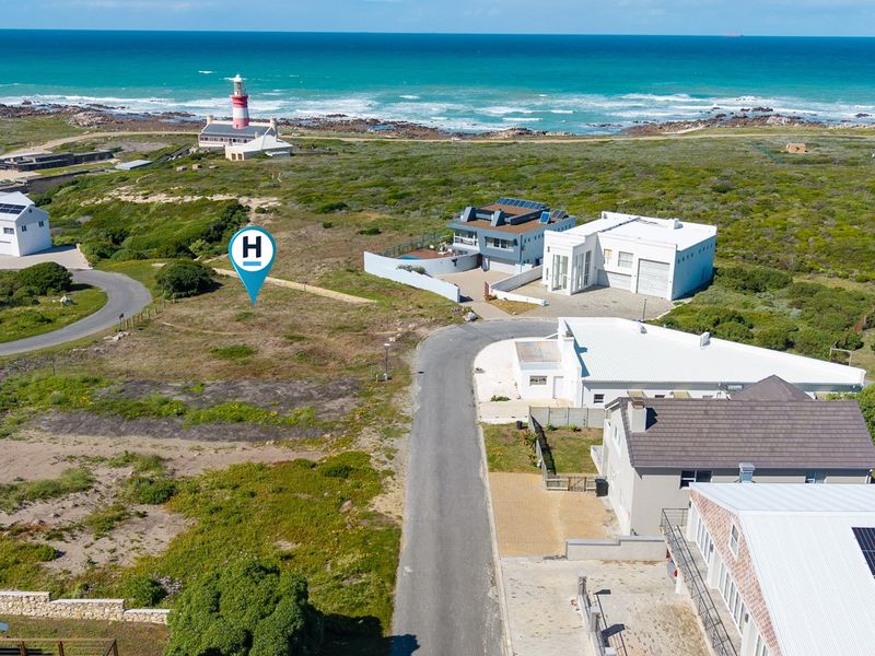 Aerial view of a vacant residential plot situated in a coastal neighborhood, offering proximity to the ocean and local lighthouse.