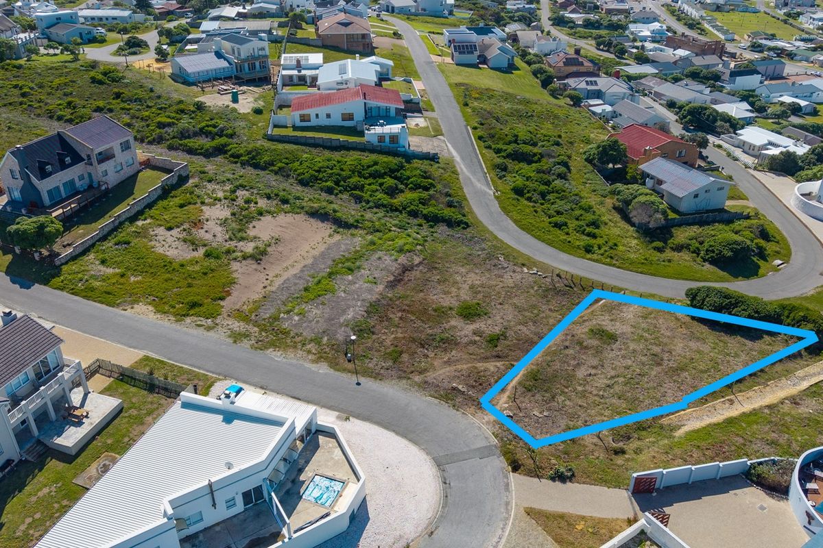 Aerial view of a vacant residential plot situated in a developed coastal neighborhood with established street access and surrounding homes.