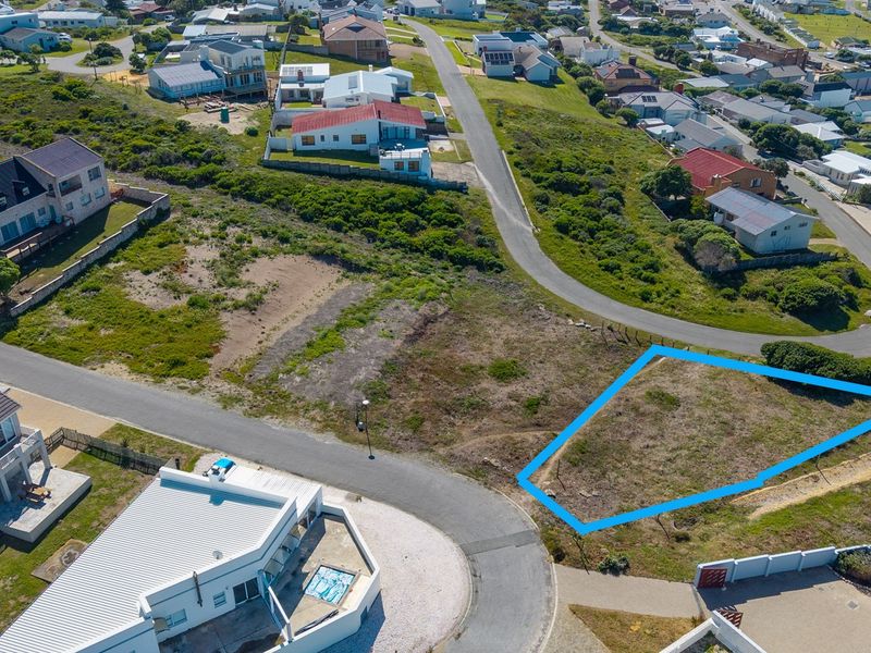 Aerial view of a vacant residential plot situated in a developed coastal neighborhood with established street access and surrounding homes.