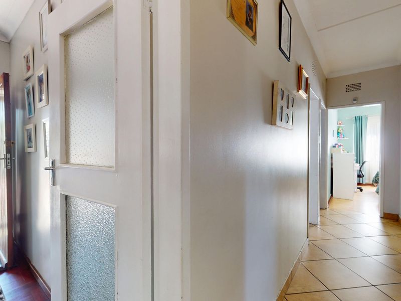 A bright hallway featuring tiled flooring and textured glass panel doors, providing access to various rooms within the home.