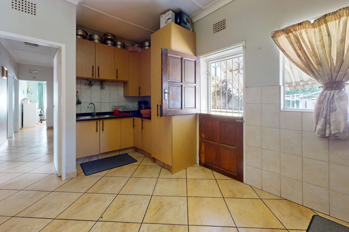 A functional kitchen featuring laminate cabinetry, tiled splashbacks, and ceramic flooring, with direct access to the exterior via a stable door.