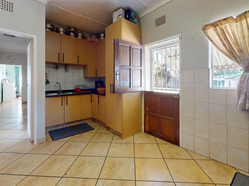 A functional kitchen featuring laminate cabinetry, tiled splashbacks, and ceramic flooring, with direct access to the exterior via a stable door.