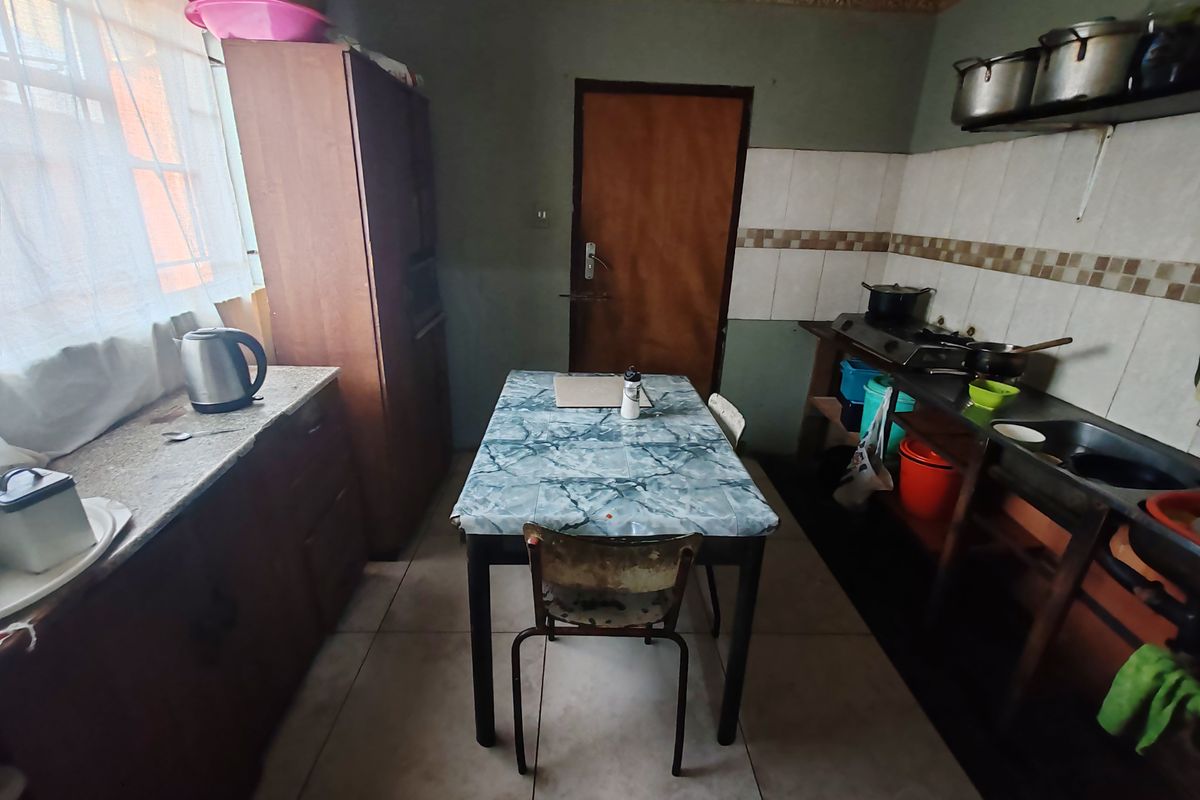 A functional kitchen featuring built-in cabinetry, a tiled backsplash, and a stainless steel sink, offering potential for modernization and aesthetic improvement.