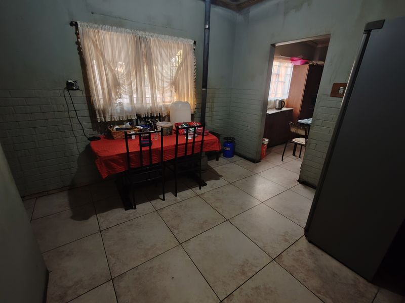 Dining area featuring tiled flooring, brick-textured walls, and a built-in wood-burning stove, offering a functional space with potential for cosmetic updates.