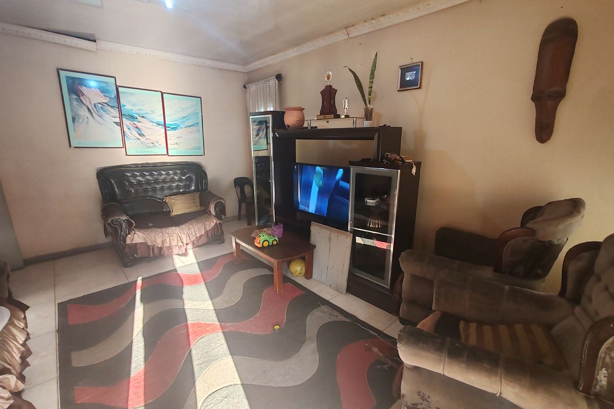 A living room featuring tiled flooring and decorative ceiling cornicing, currently showing signs of wear on the walls and ceiling requiring cosmetic attention.