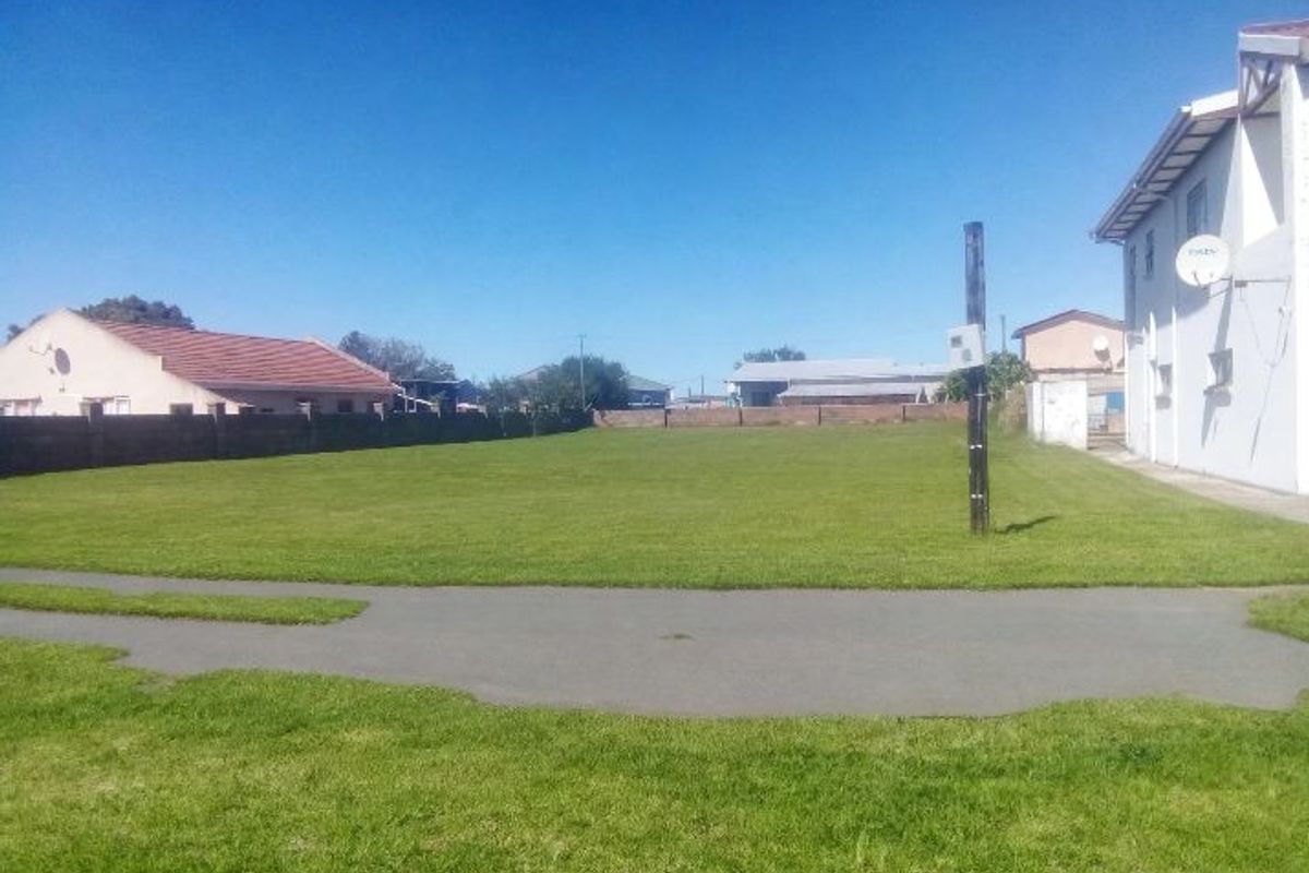A spacious, well-maintained vacant residential plot featuring a level lawn, boundary walls, and a paved driveway area.