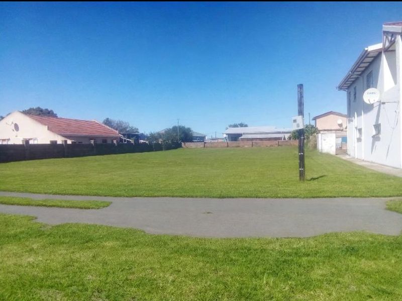 A spacious, well-maintained vacant residential plot featuring a level lawn, boundary walls, and a paved driveway area.