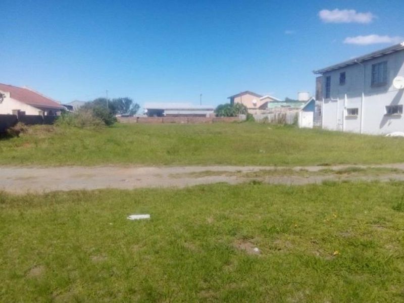 A vacant residential plot of land featuring a grass lawn, situated between existing neighboring properties.