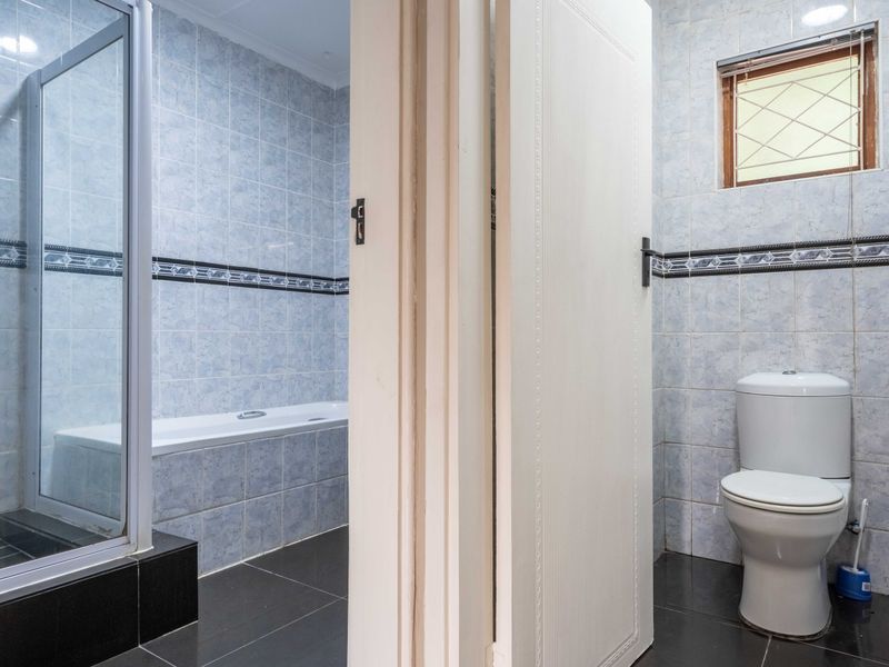 A functional bathroom featuring a shower enclosure, bathtub, and toilet with tiled finishes throughout.