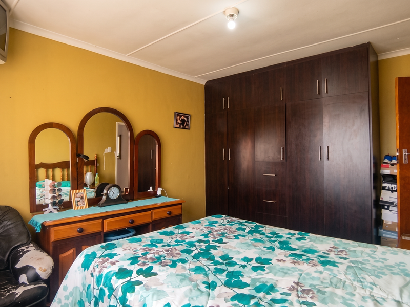 A bedroom featuring a large dark wood built-in wardrobe and cove cornice detailing.