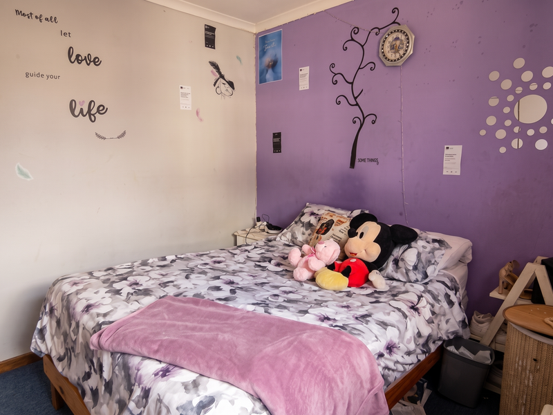 A bedroom featuring a dual-tone wall finish with purple and neutral paint, carpeted flooring, and standard residential lighting.