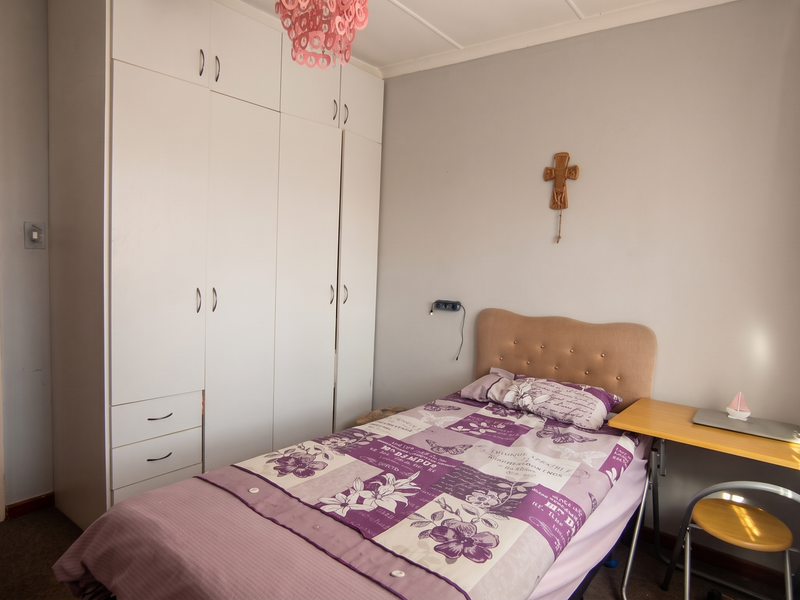 A functional bedroom featuring a white built-in wardrobe and carpeted flooring, offering a practical layout for a single occupant.
