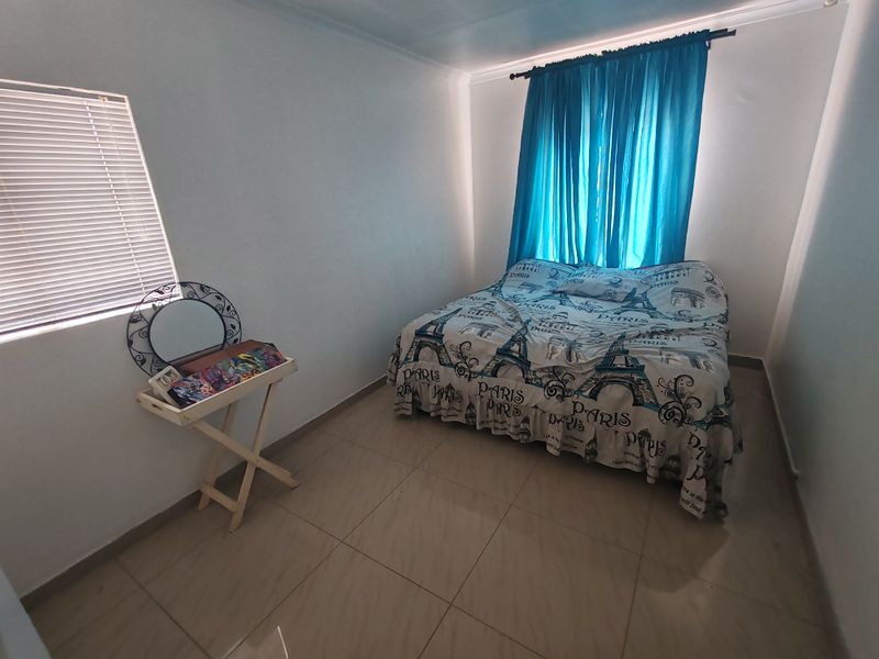 A functional bedroom featuring tiled flooring and window treatments, providing a neutral base for personalization.