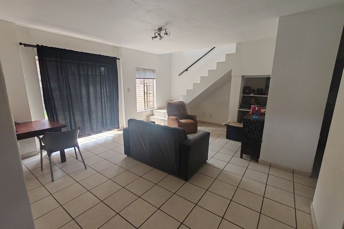 Open-plan living area featuring tiled flooring, a staircase leading to the upper level, and a sliding door providing access to the exterior.