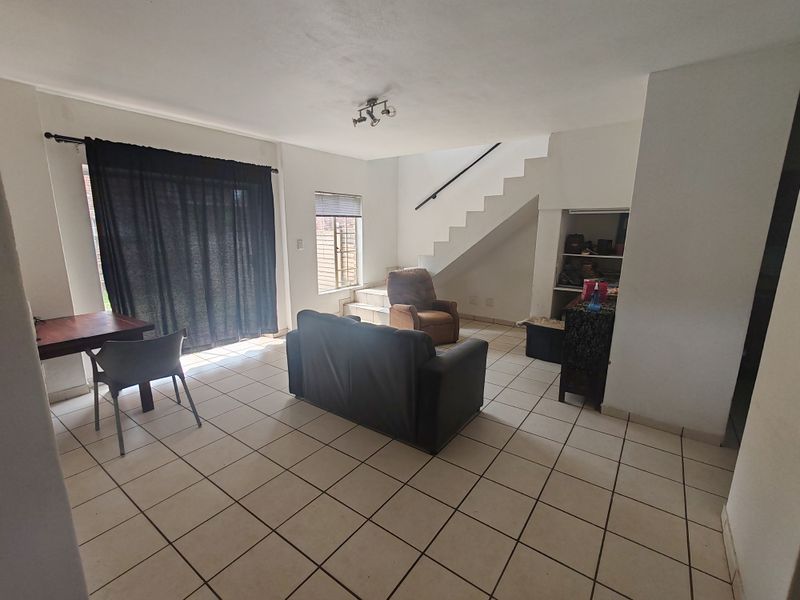 Open-plan living area featuring tiled flooring, a staircase leading to the upper level, and a sliding door providing access to the exterior.