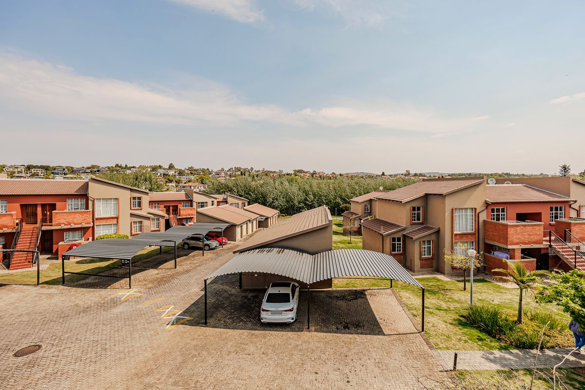 Aerial view of an apartment complex featuring multiple residential buildings, covered parking carports, and well-maintained paved driveways and landscaped grounds.
