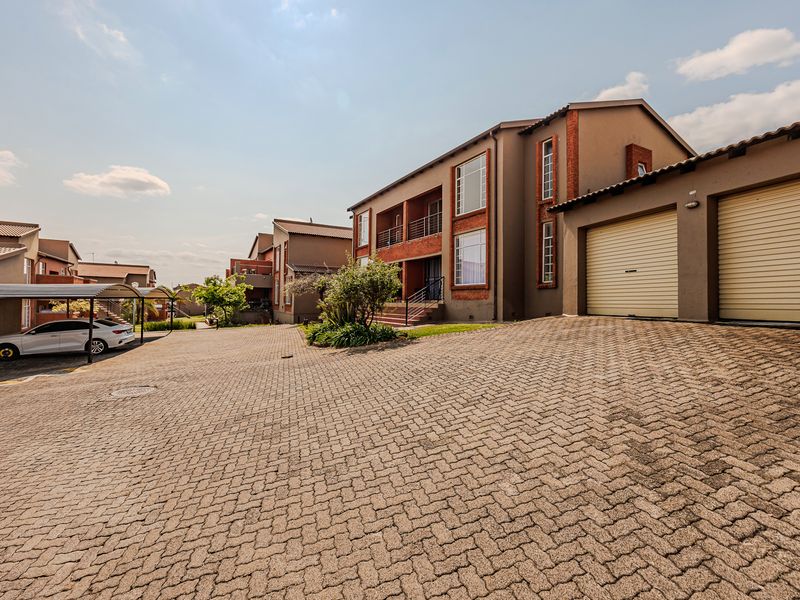 Exterior view of a residential apartment complex featuring paved driveway, double garage, and covered parking bays.
