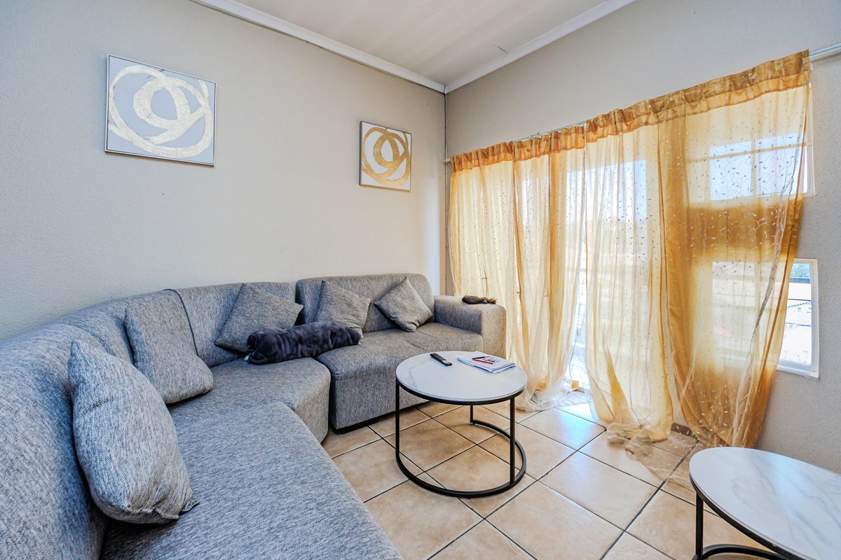A living room featuring tiled flooring and a sliding glass door providing access to an outdoor area.