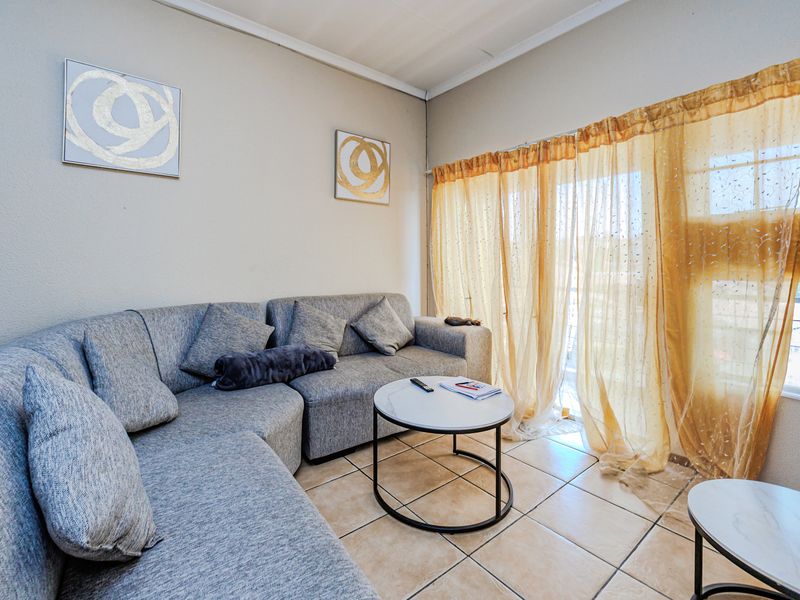 A living room featuring tiled flooring and a sliding glass door providing access to an outdoor area.