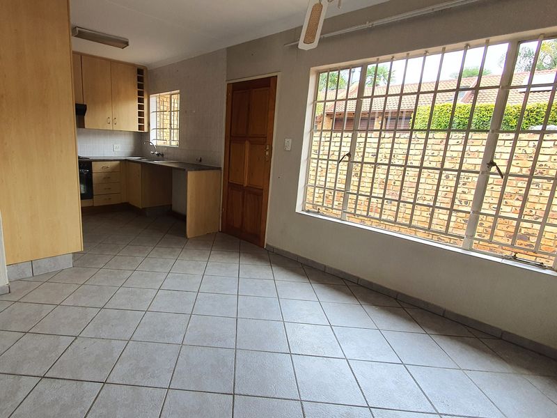 Open plan kitchen and living area featuring tiled floors, built-in cabinetry, integrated oven, and large windows with security bars.