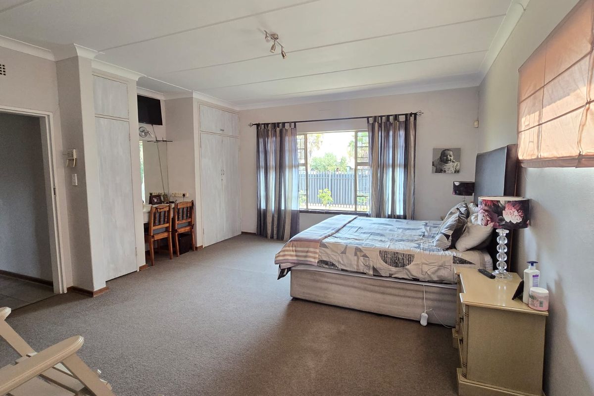 Spacious bedroom featuring built-in cupboards, a dedicated vanity area, and large windows allowing for natural light.