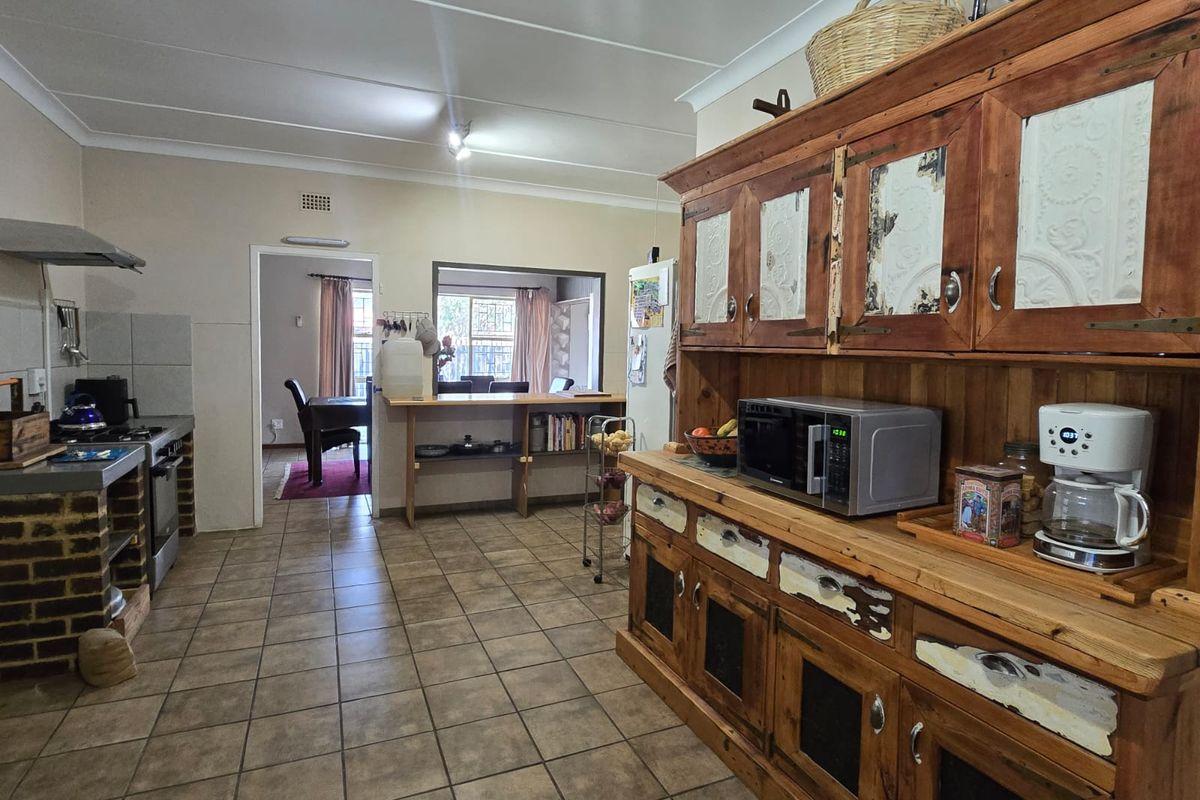 A functional kitchen featuring tiled flooring, built-in cabinetry, and a gas stove, with an open-plan layout connecting to the adjacent dining area.