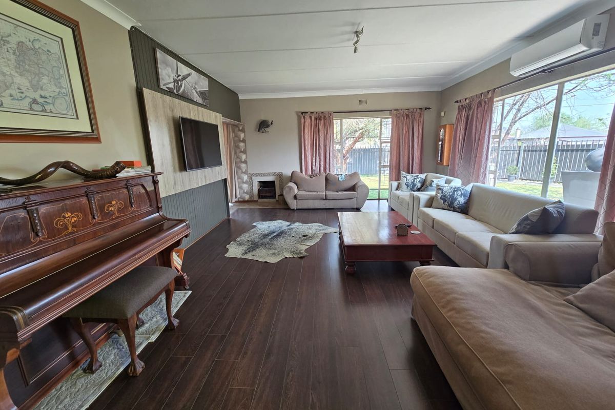 Spacious living room featuring dark laminate flooring, a built-in feature wall, and large sliding glass doors providing natural light and garden access.