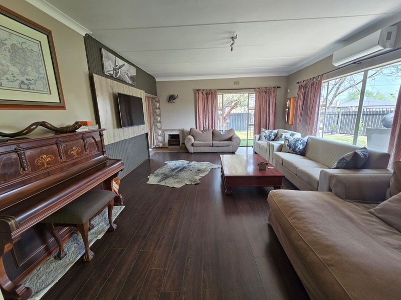 Spacious living room featuring dark laminate flooring, a built-in feature wall, and large sliding glass doors providing natural light and garden access.