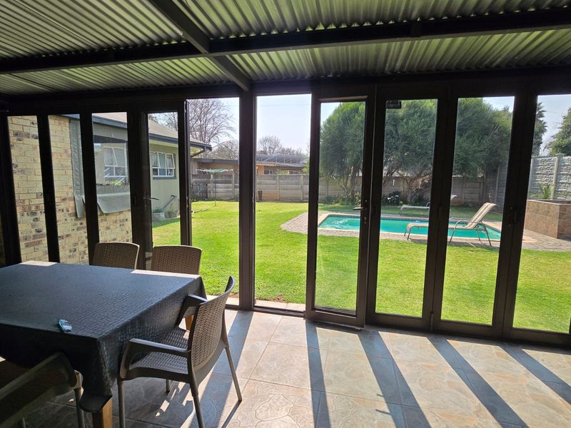 Covered patio featuring tiled flooring and aluminium stacker doors, providing seamless access to the garden and swimming pool area.