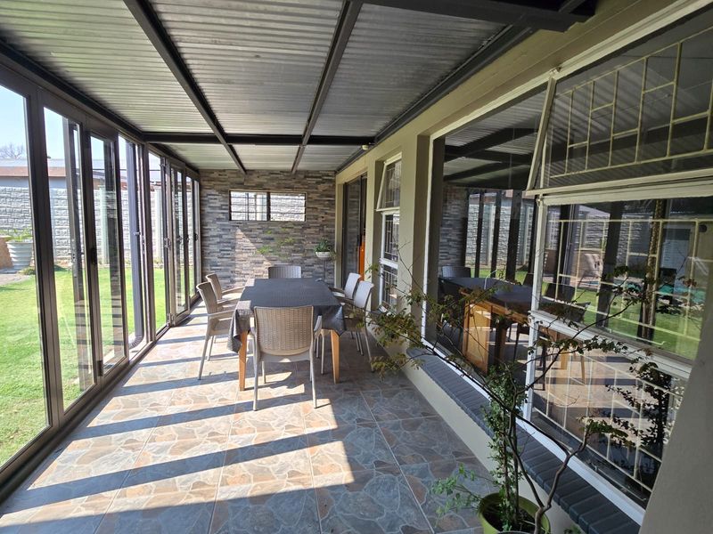 A covered patio area featuring a stone-clad feature wall, tiled flooring, and aluminium folding doors that open out to the garden.