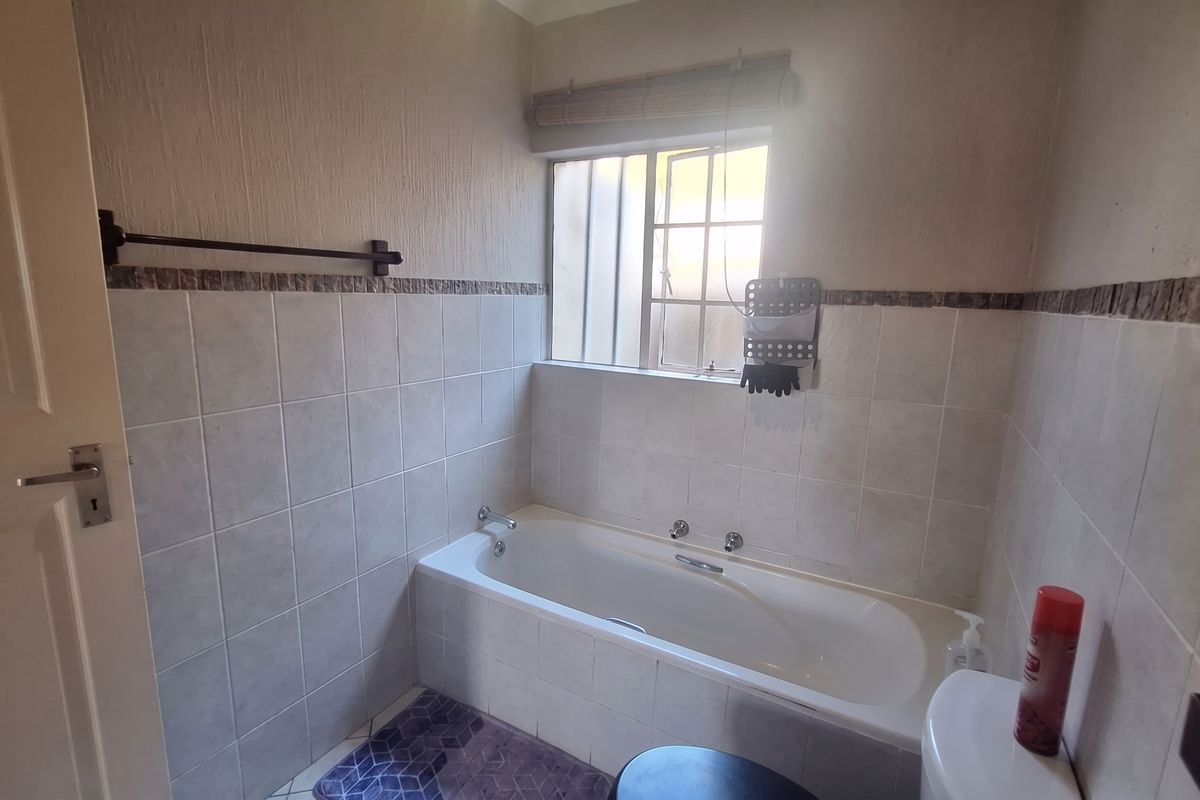 A functional bathroom featuring a built-in bathtub, tiled wall finishes, and a window for natural light.
