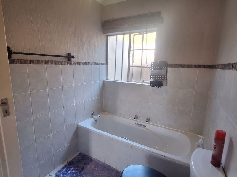 A functional bathroom featuring a built-in bathtub, tiled wall finishes, and a window for natural light.