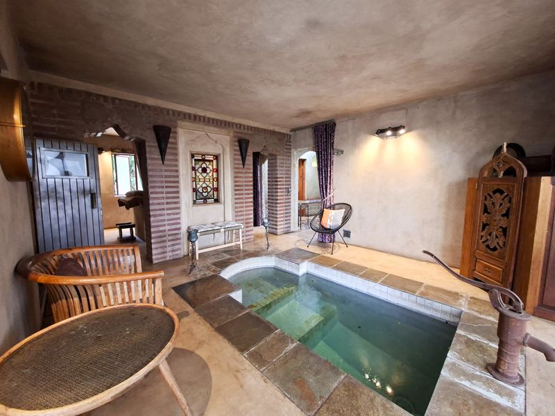 Unique indoor plunge pool area featuring rustic exposed brick archways, stone tiling, and decorative stained glass accents in a character-filled setting.