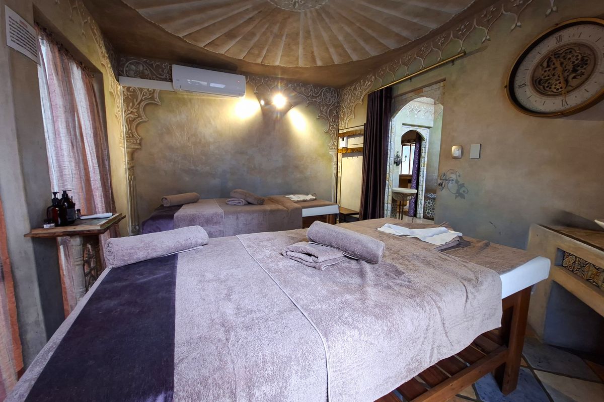 A uniquely styled bedroom featuring an ornate domed ceiling, decorative wall finishes, and split-system air conditioning, currently set up as a treatment space.