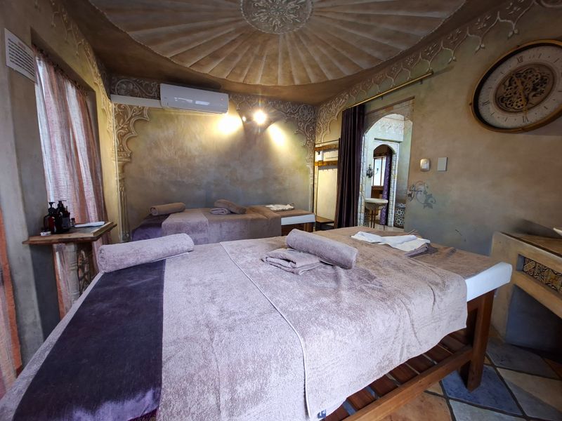 A uniquely styled bedroom featuring an ornate domed ceiling, decorative wall finishes, and split-system air conditioning, currently set up as a treatment space.