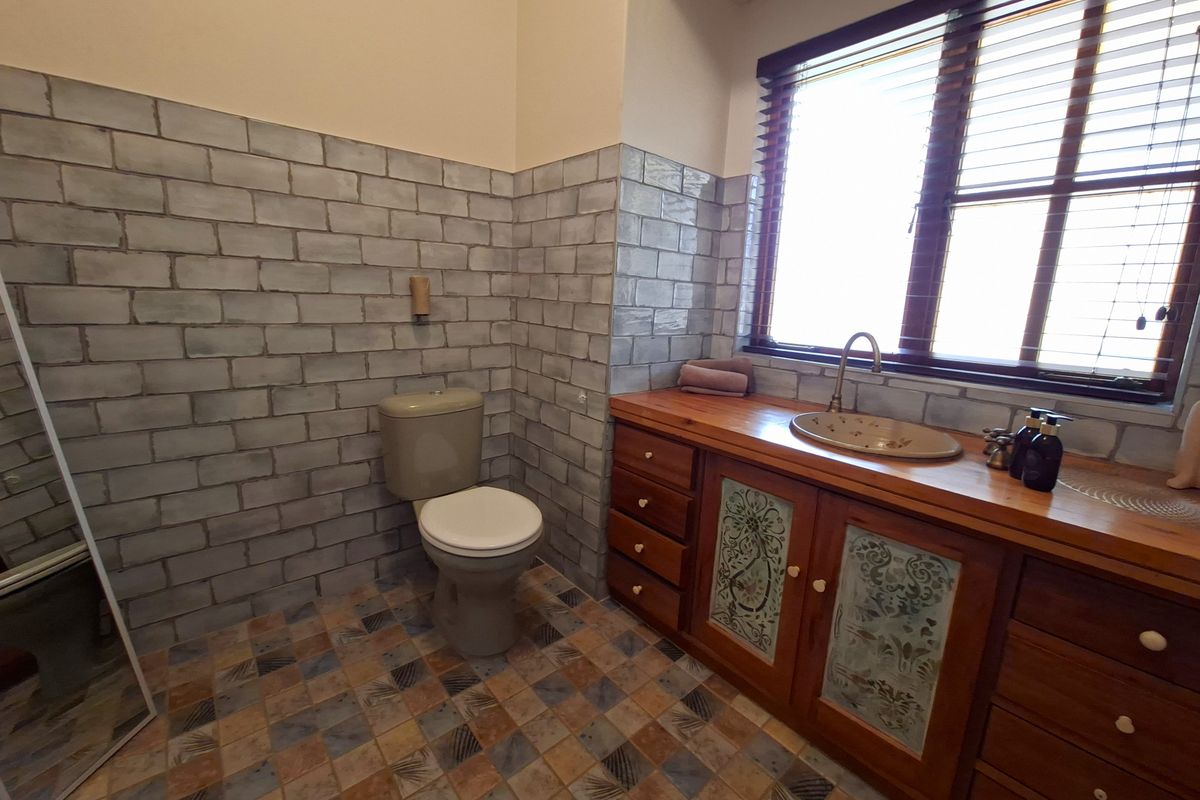 A bathroom featuring a wooden vanity with a built-in basin, tiled walls, and patterned floor tiles.