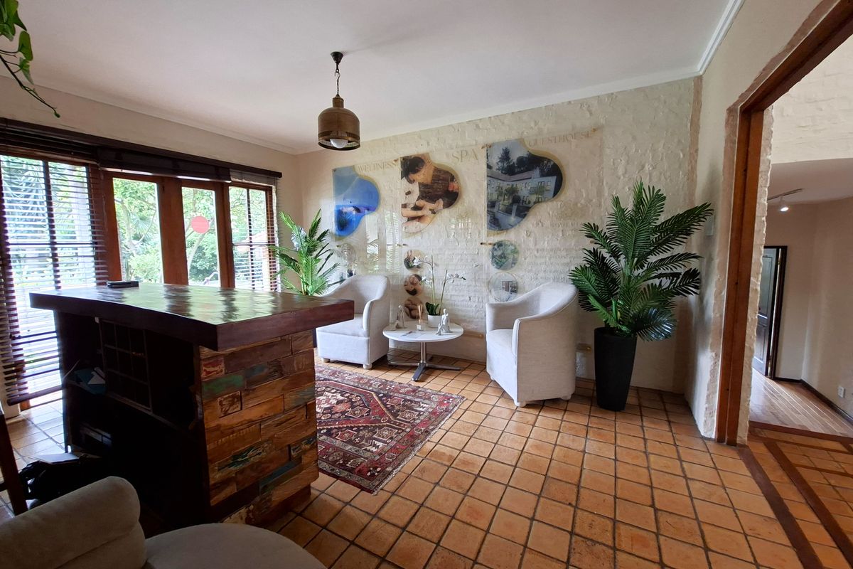 A living area featuring terracotta tile flooring, an exposed brick wall, and a built-in wooden bar counter with natural light from large windows.