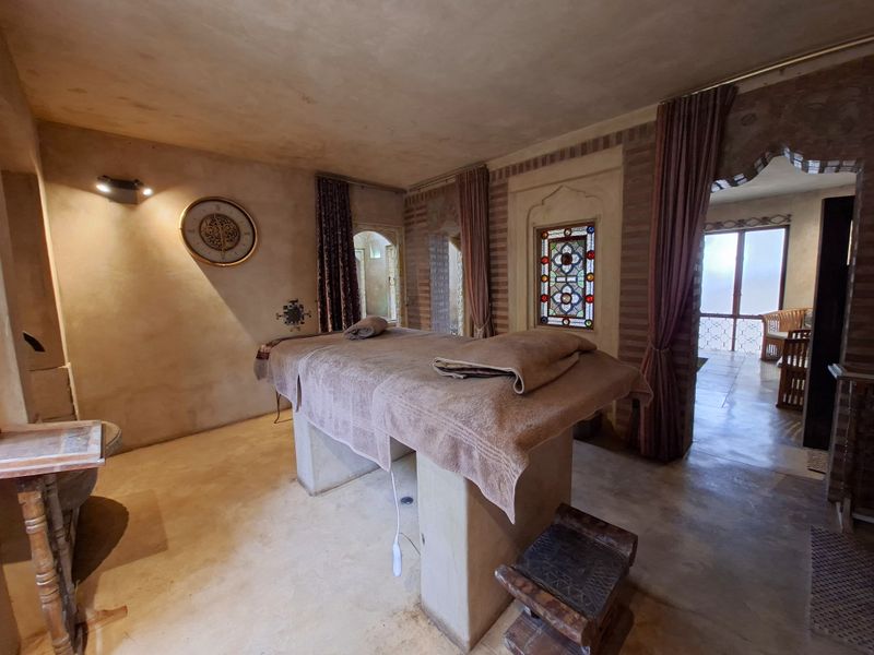 A uniquely styled room featuring decorative stained glass, arched architectural details, and textured plaster walls, currently set up as a treatment space.