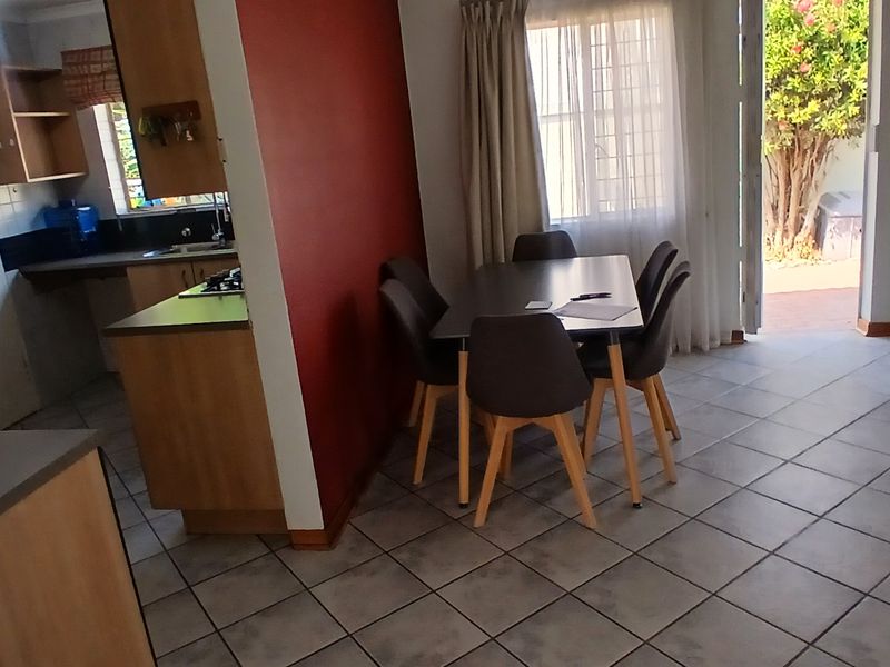 Open-plan living and dining area featuring tiled floors, a functional kitchen with built-in cabinetry, and direct access to an outdoor patio area.