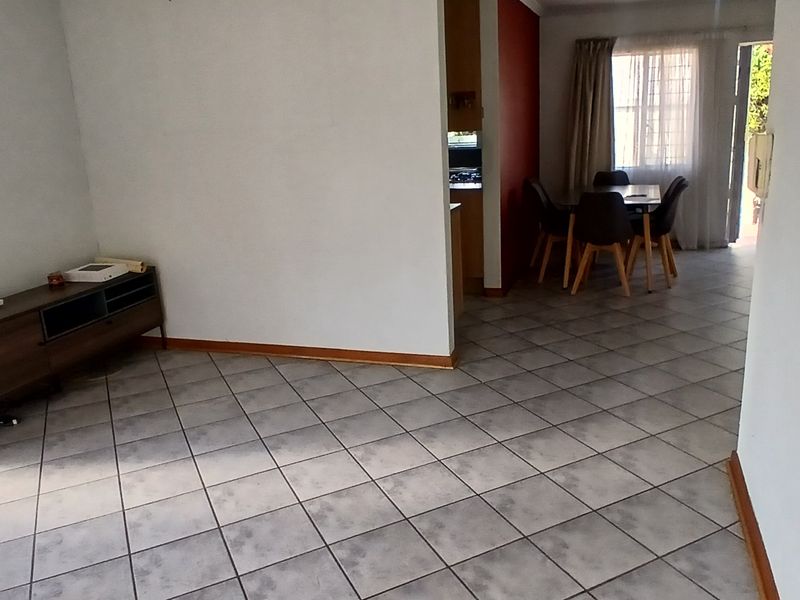 Open plan living and dining area featuring neutral walls and tiled flooring, providing a functional space with direct access to the exterior.