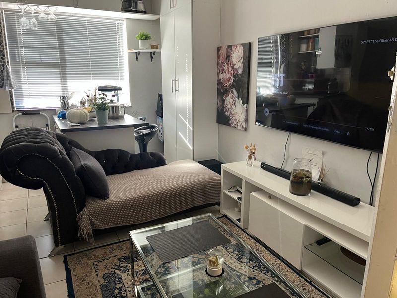 Open plan living area featuring tiled flooring, built-in cabinetry, and natural light through venetian blinds.